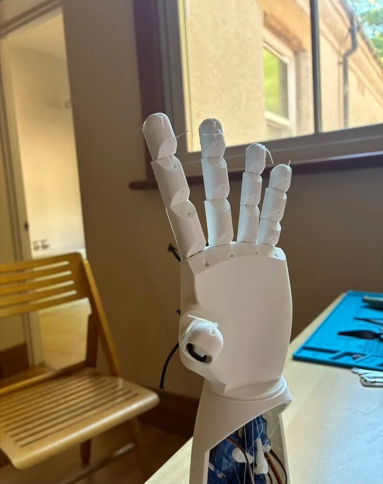 White printed robotic hand mounted above its actuation mechanism.